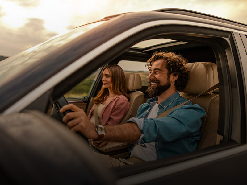 Noleggio auto a lungo termine Arval: uomo alla guida di un'auto e donna sorridente sul sedile del passeggero